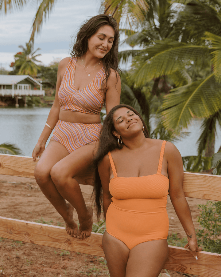 Two girls wearing bright swimsuits near the water in Hawaii