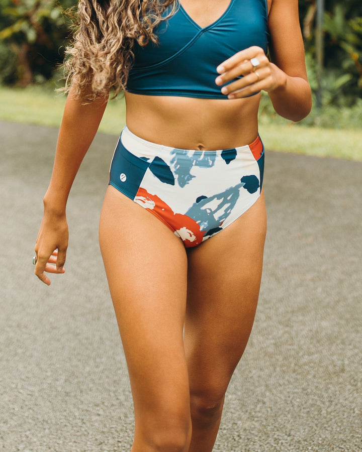 Women walking in red, white, and blue high waisted swimsuit bottoms with a yoga pocket detail.