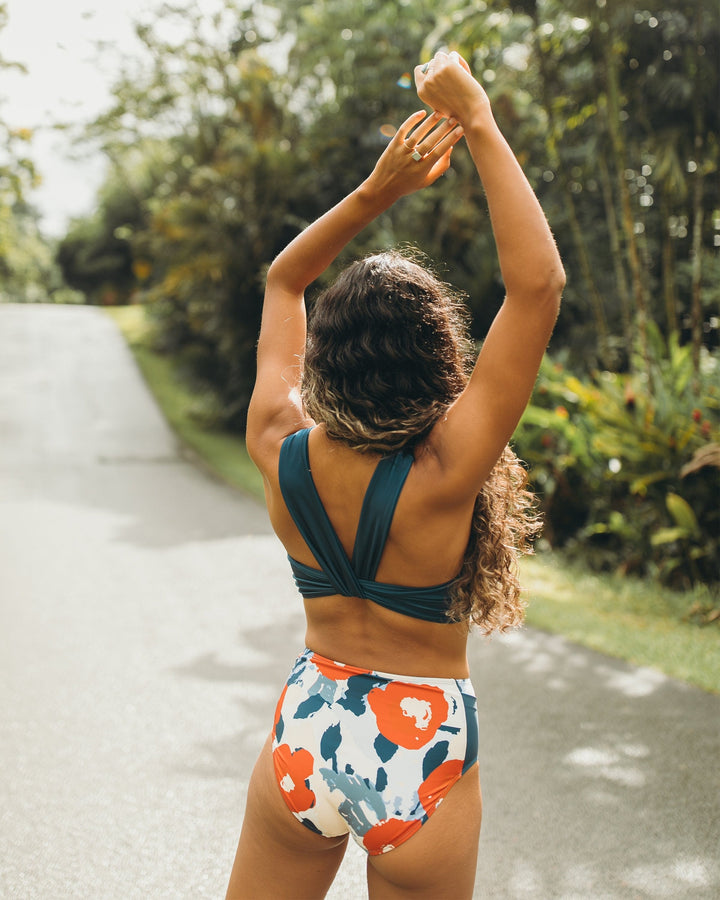 A women wearing red, white, and blue high waisted swimsuit bottoms with a yoga pocket detail.