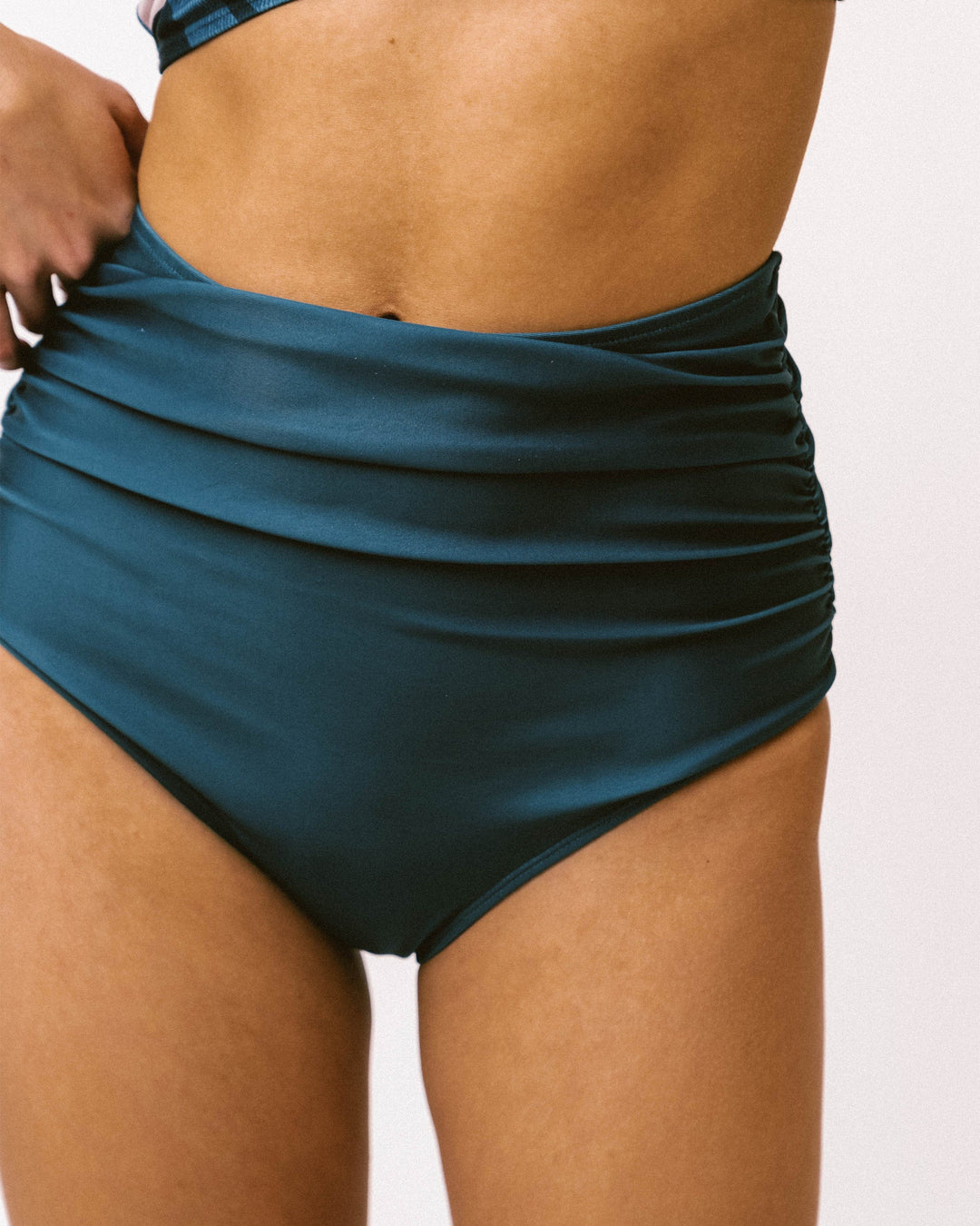 A close up photo of blue high waisted ruched swimsuit bottoms.