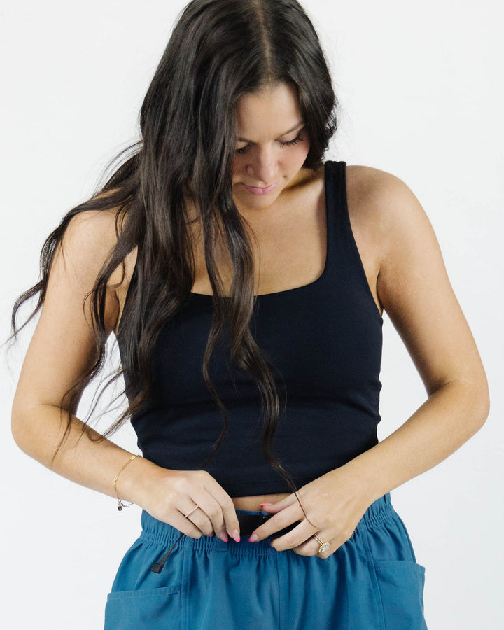 A studio image of a woman wearing a black work out crop top.