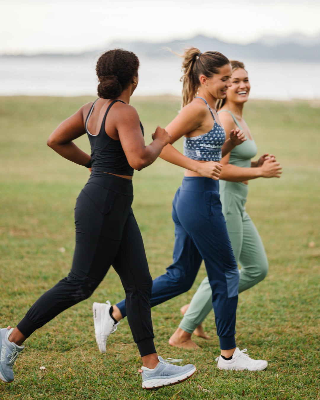 A group of women wearing athletic clothes jogging near the beach.