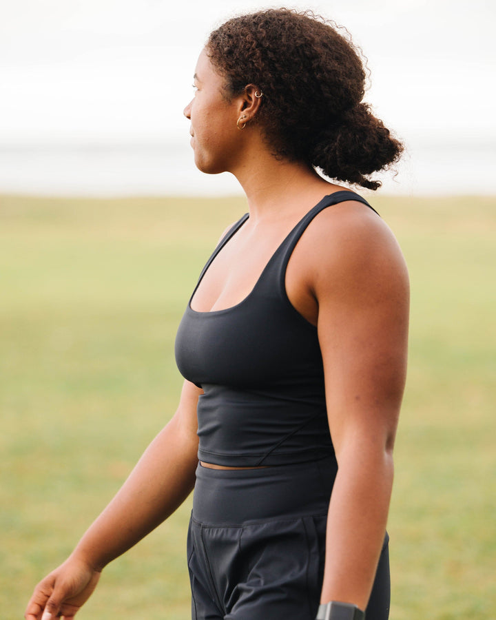 A woman wearing a black cropped sports bra.