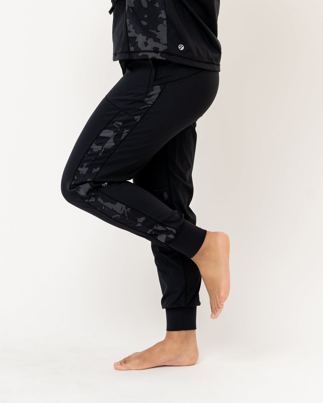 A studio image of a black exercise jogger with a grey and black floral patterned detail running down the side of the leg.