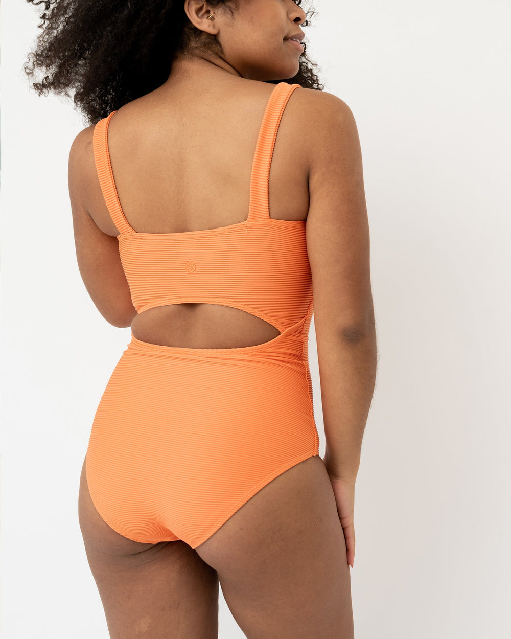 Back View Studio picture of a girl wearing a textured orange one piece swimsuit