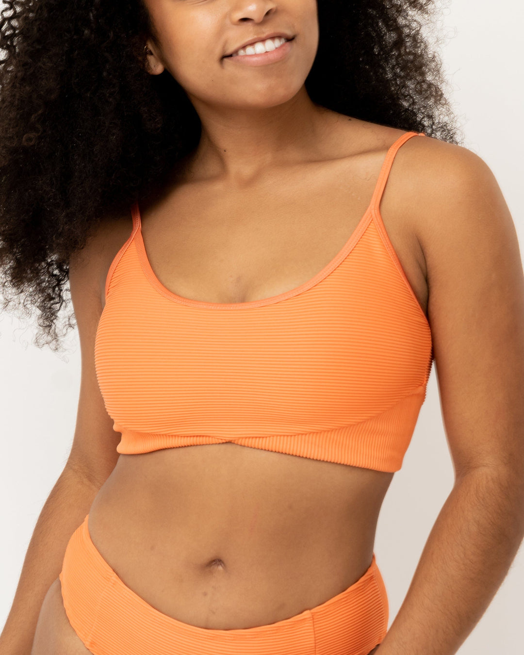 Front view Studio picture of a girl wearing textured orange bikini top
