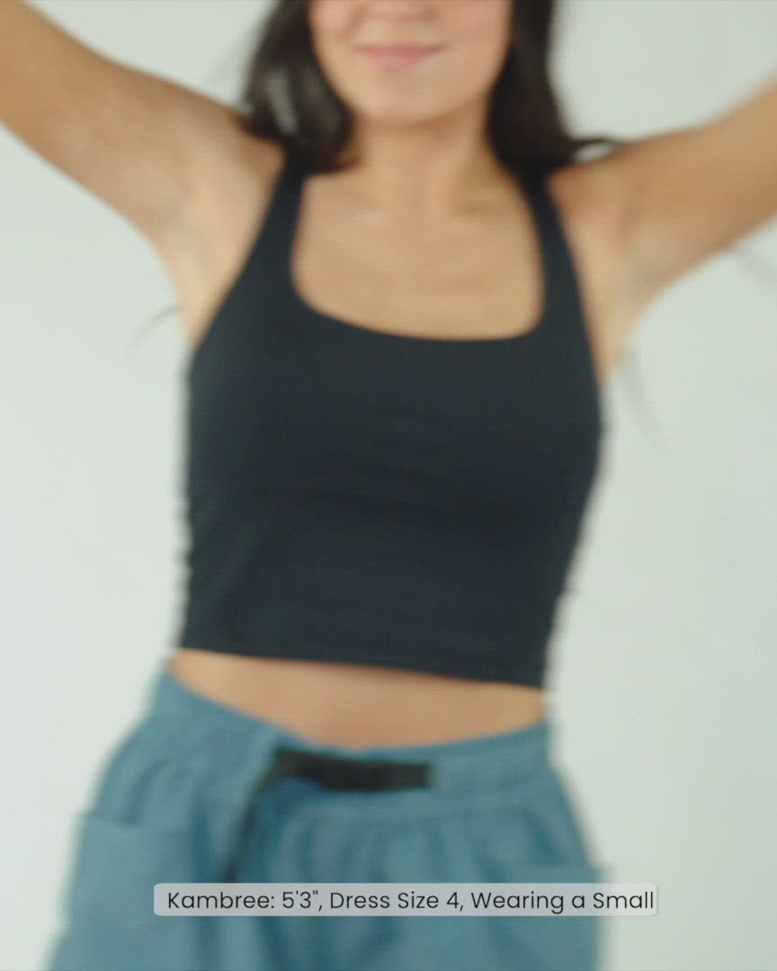 A video of a woman modeling a black cropped sports bra.