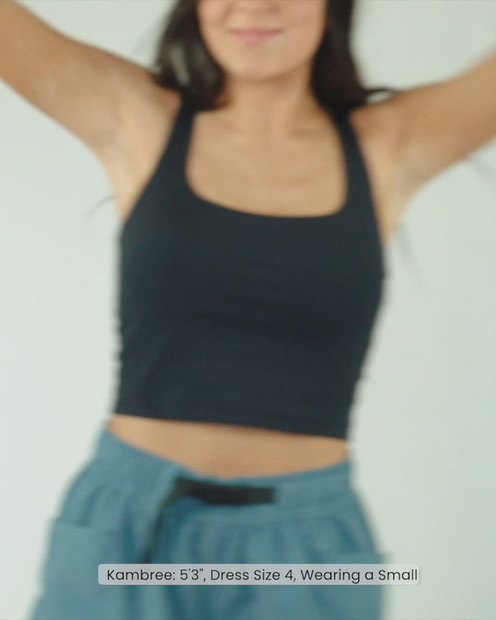 A video of a woman modeling a black cropped sports bra.