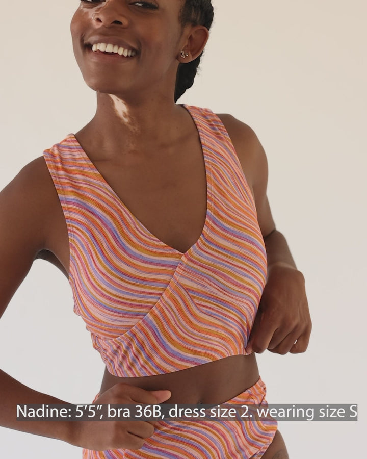 Video showing a girl wearing a retro pink, blue, purple and orange wave bikini top